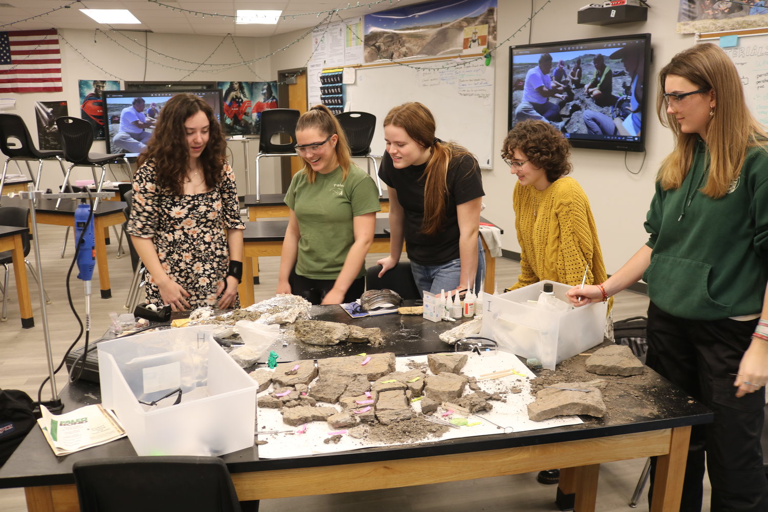 Members of the Nease High paleo club unwrap and clean fossilized dinosaur bones. The club is currently learning the cleaning and preserving process prior to their trip to Montana in July to search for dinosaur fossils themselves.